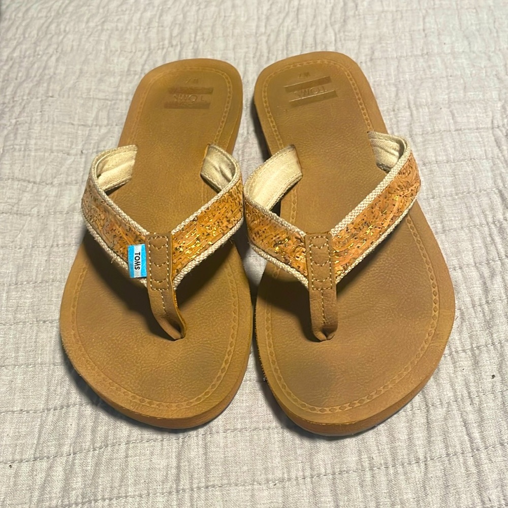 Tom’s tan and gold flip flops, size 7